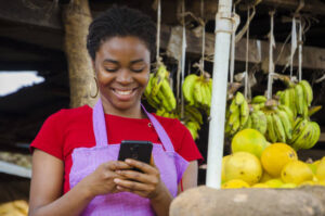 A young beautiful African market seller feeling happy about what she saw on her cellphone